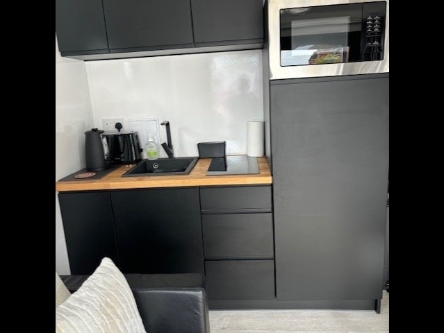 Kitchenette counter with black sink and wooden worktop